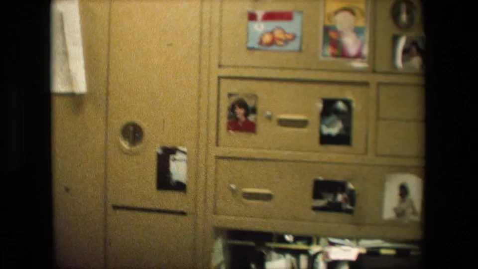 Wood-toned storage cabinet or dresser in a private room, decorated with personal photographs, small drawings or papers, and drawer pulls.