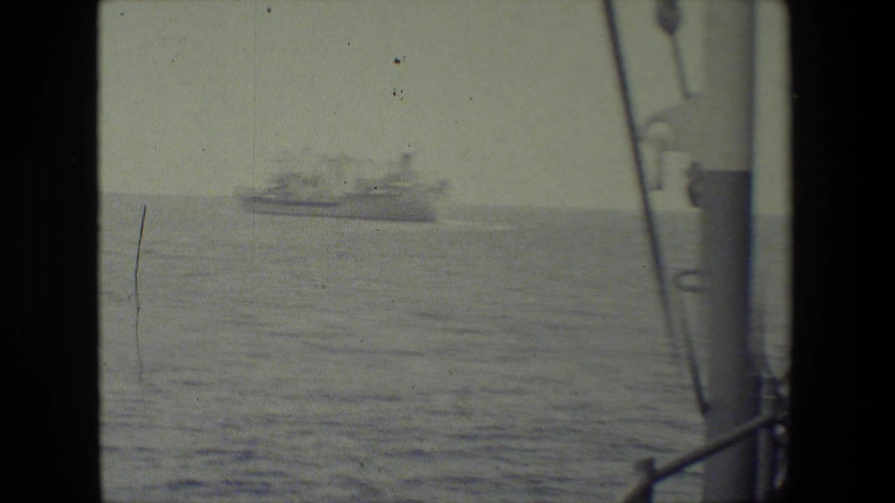 Distant vessel at sea with ship rigging and deck structure along the right side of the frame.