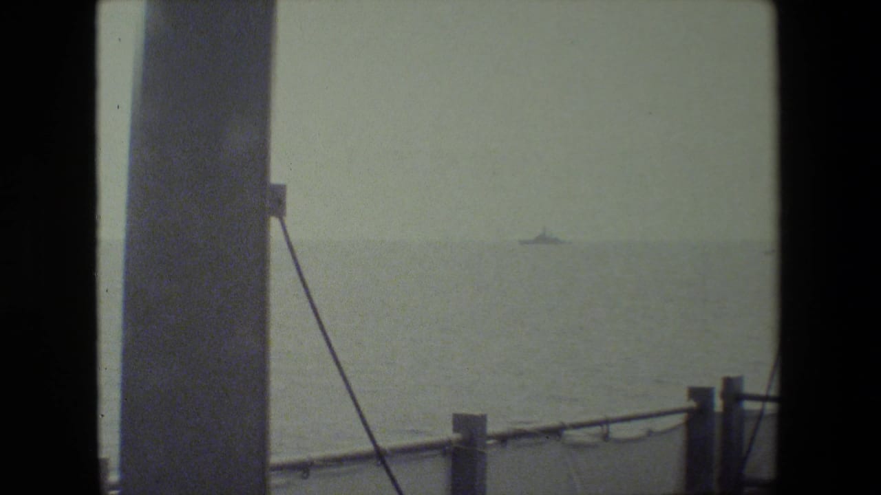 Distant vessel on the horizon seen past ship structure and railing.