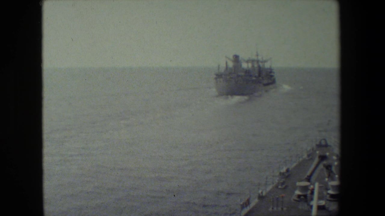 Large vessel passes across open water beyond the filming ship's bow.