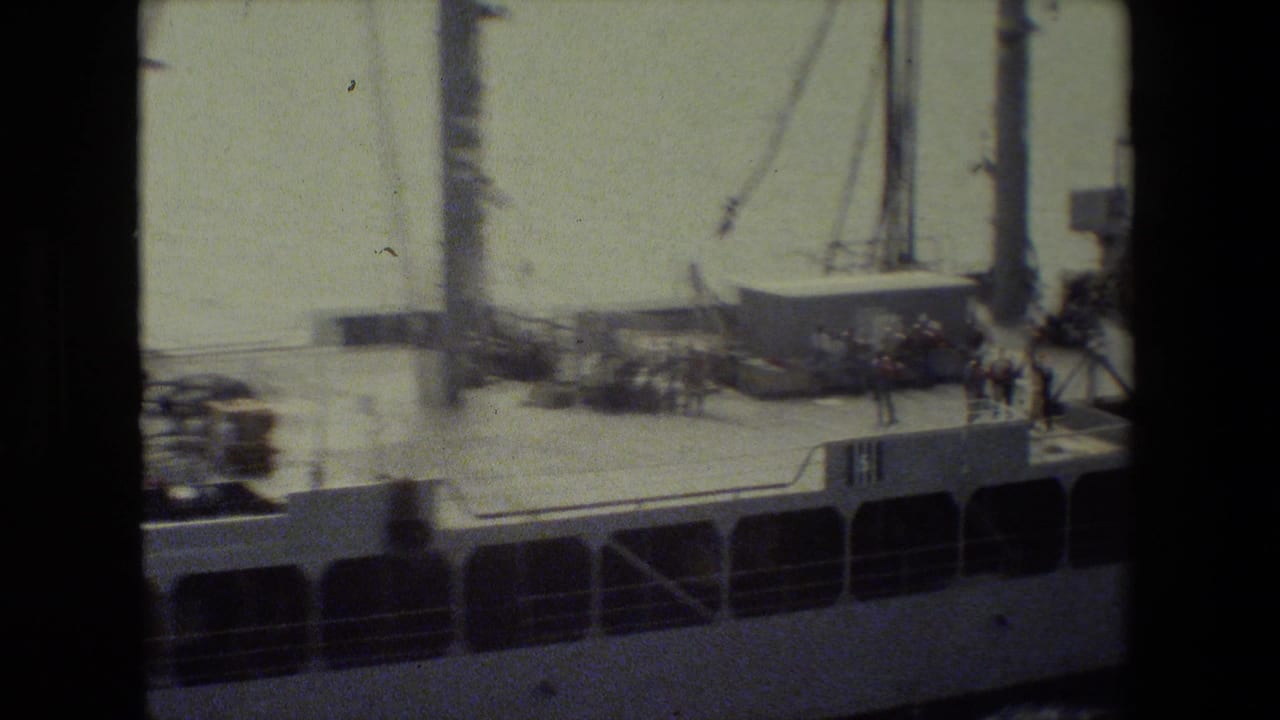 Deck section of a large vessel with equipment and a small group near the rail.