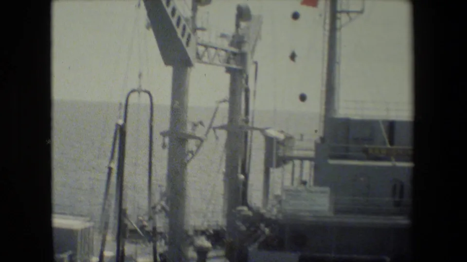 1981 San Diego naval footage frame showing mast hardware, vertical railings, pipes, deck equipment, and part of the vessel’s superstructure.