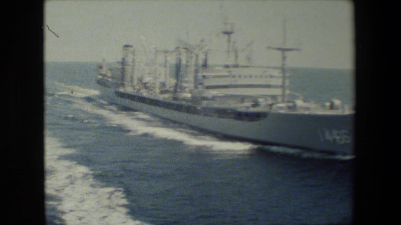 White naval ship angled across the ocean with hull number partly visible near the bow.