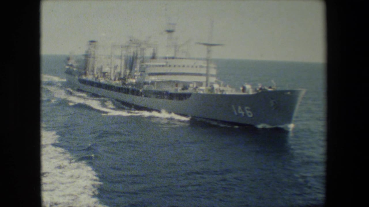 A gray U.S. Navy cargo or support ship marked with hull number 146 moves across open water in 1981-era 8mm footage, leaving a foamy wake behind it.