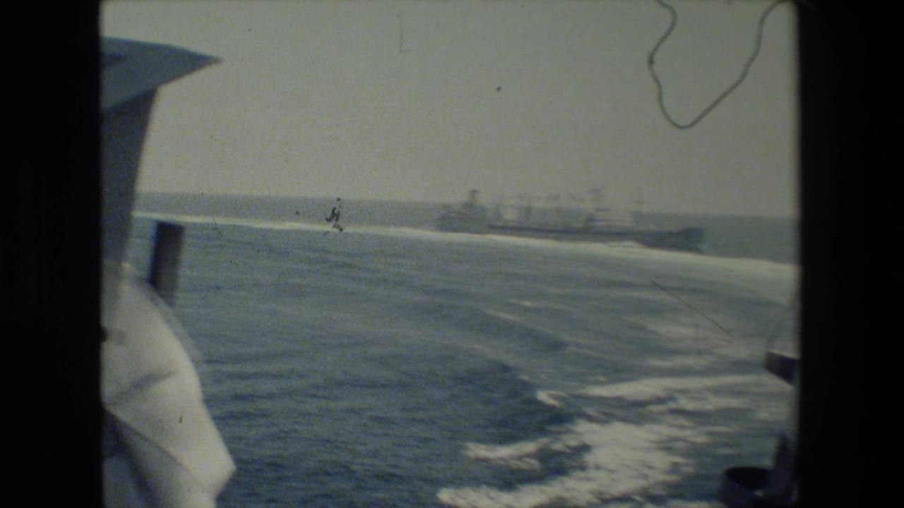 Open water and ship wake with distant naval vessels near the horizon.