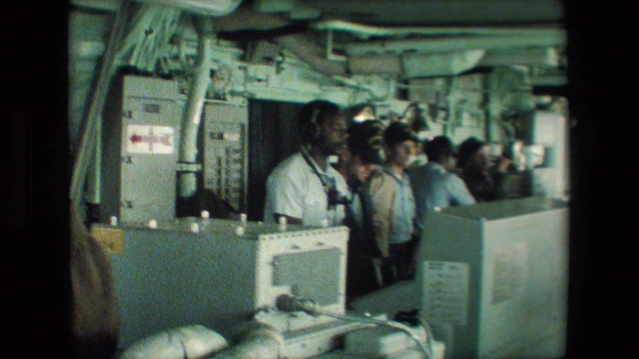 Uniformed naval personnel appear at consoles in a cramped submarine control room, with overhead piping, wall panels, and equipment visible in the 1981 source footage.