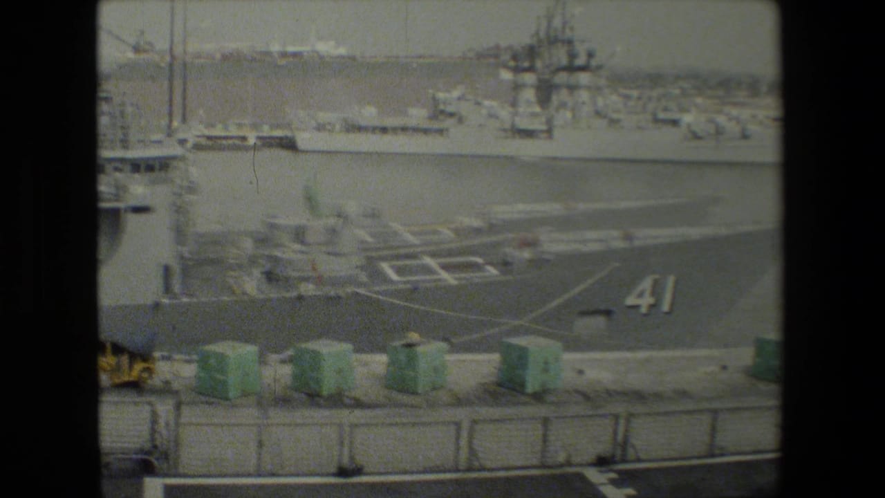Naval vessel with deck markings and the number 41 near dockside containers.