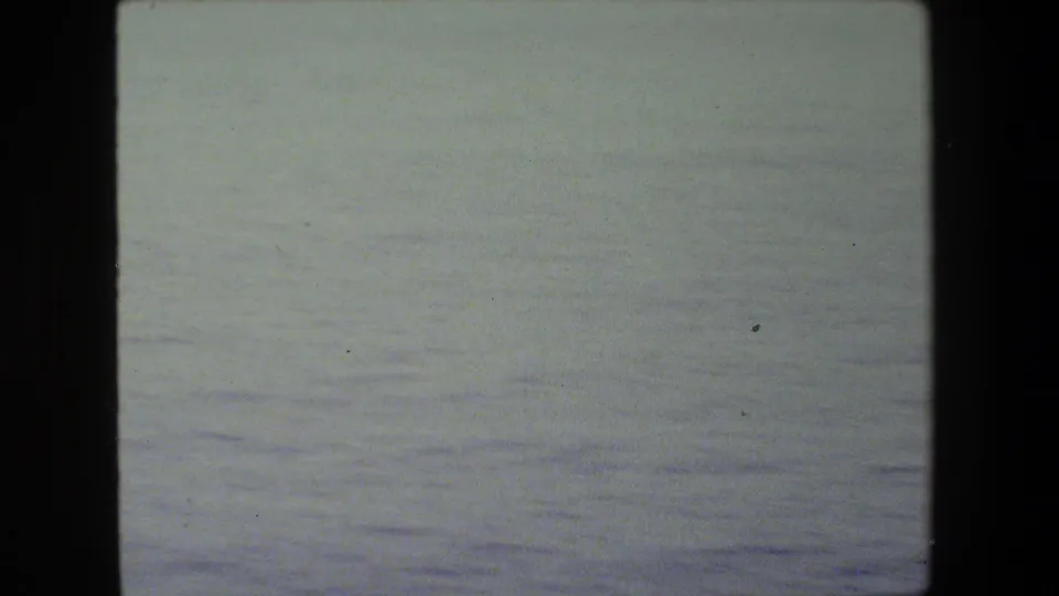 Mostly open sea in a faded 8mm frame, with no clear people or ship details visible beyond the contact-sheet border and film texture.