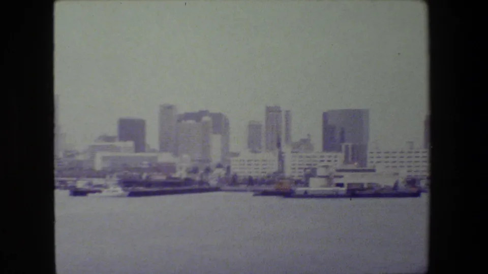 San Diego harbor at the end of the pan, showing docked ships, port buildings, open water, and a dense early-1980s skyline in soft 8mm color.