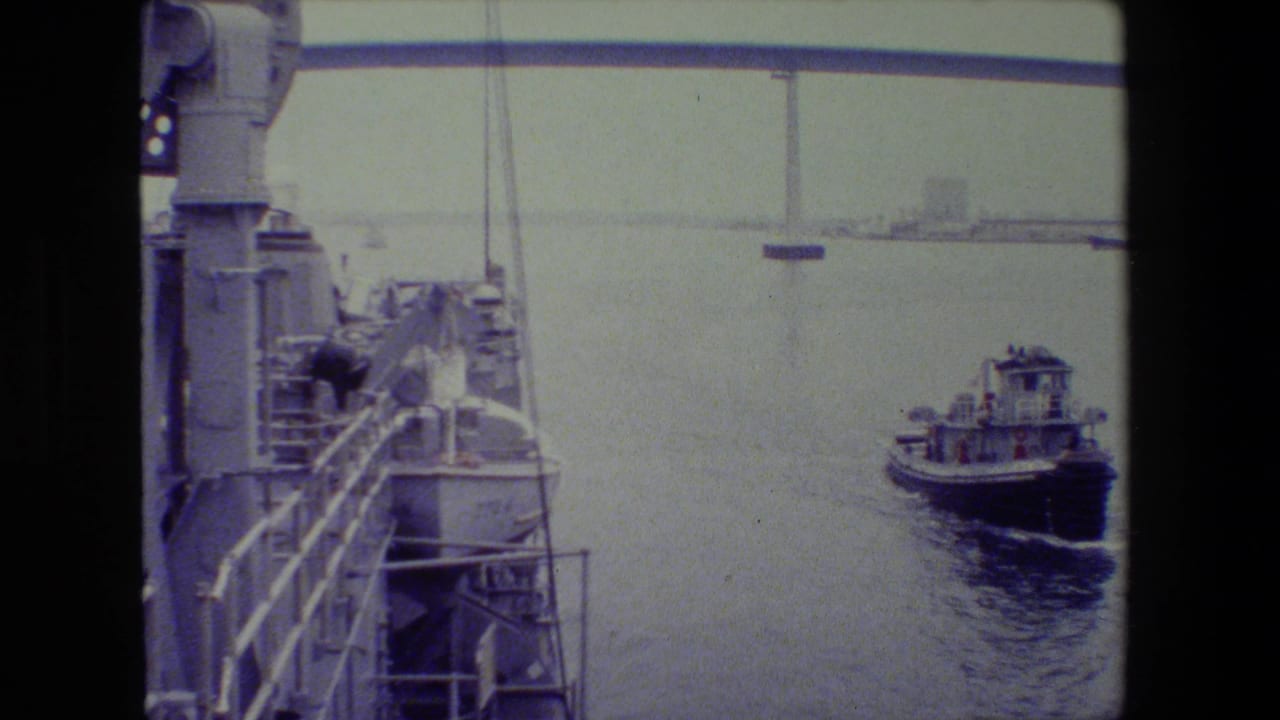 Tugboat farther out in the harbor near ship deck equipment.
