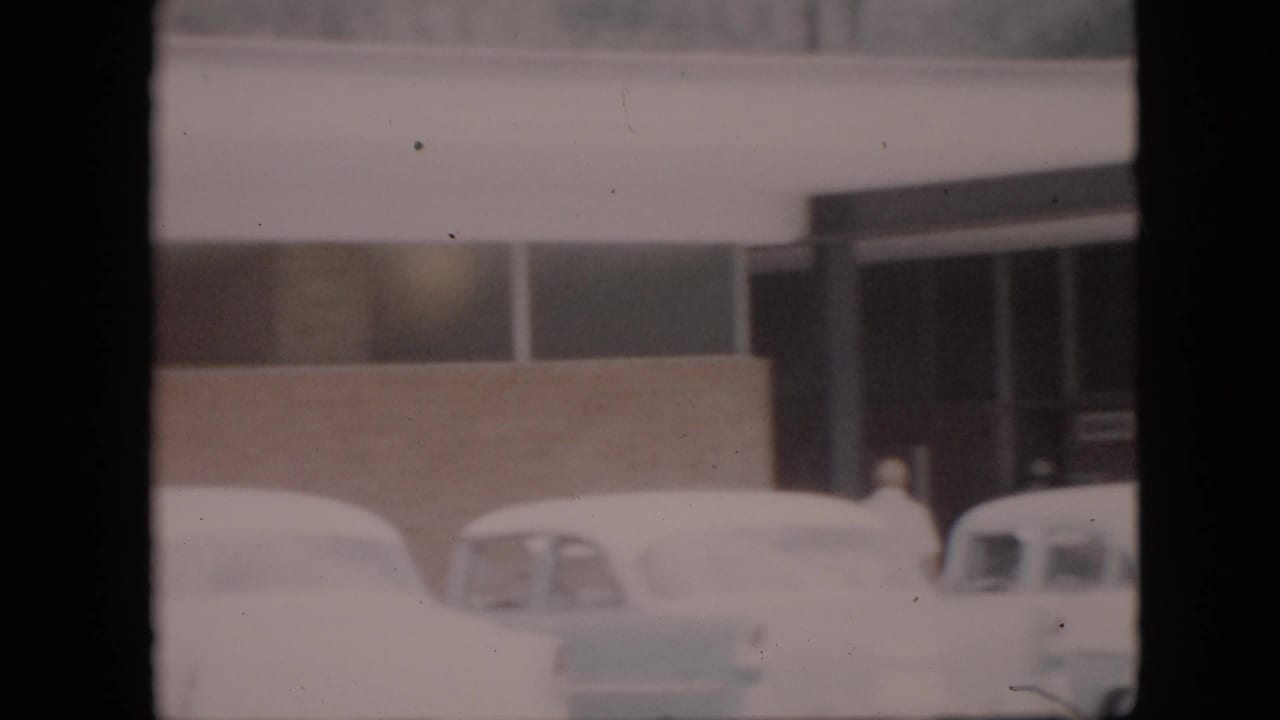 Snow-covered late-1950s cars sit outside a low roadside commercial building in Pennsylvania footage identified as 1958.