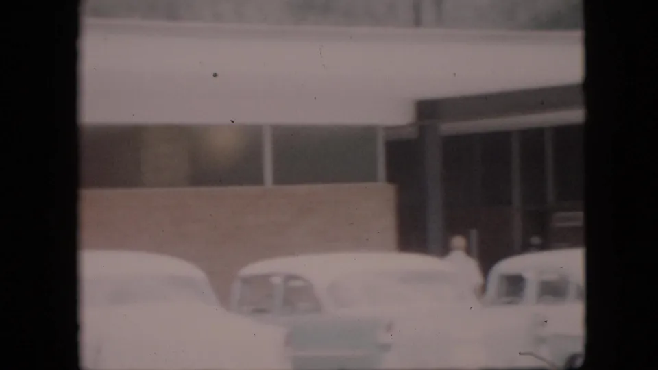 Snow-covered late-1950s cars sit outside a low roadside commercial building in Pennsylvania footage identified as 1958.