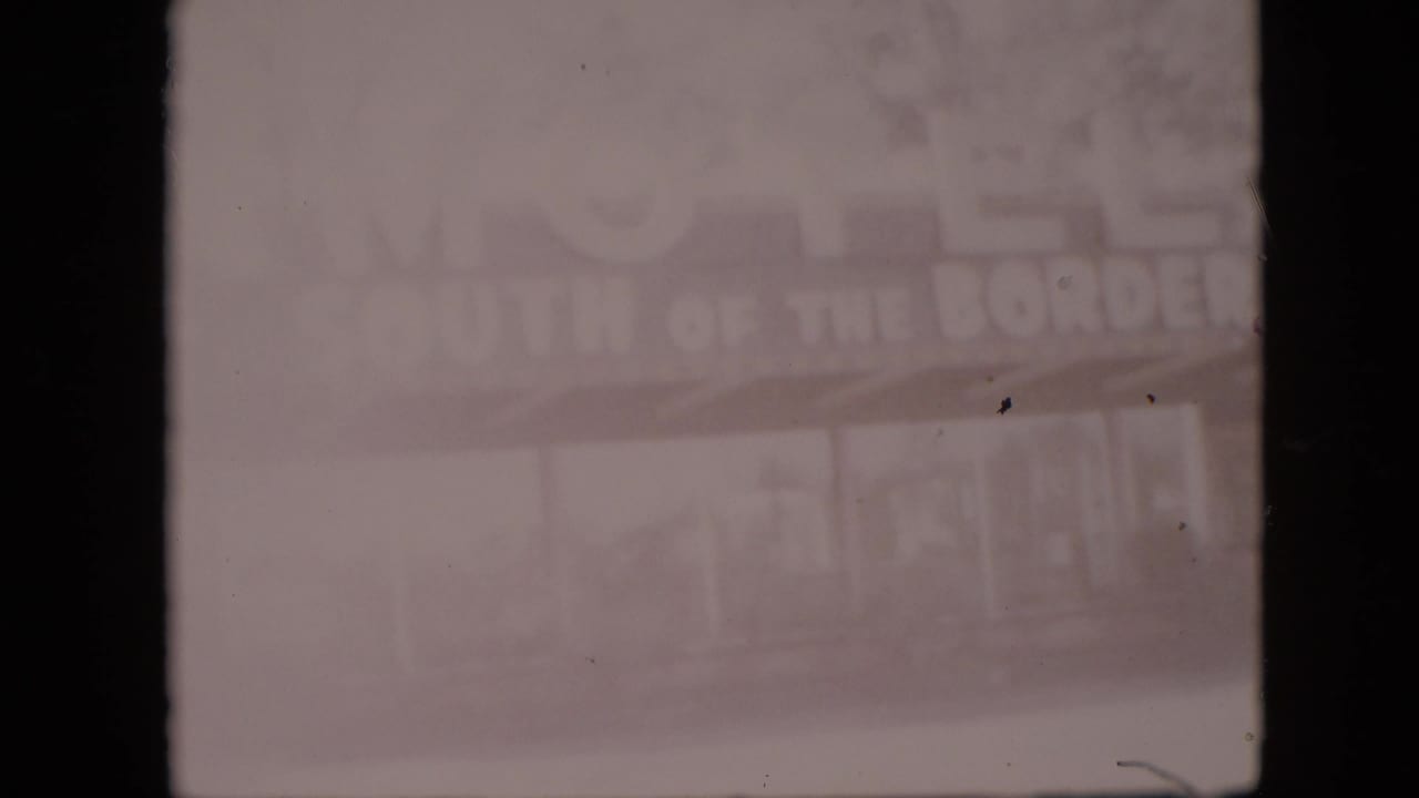 Faded 1958 8mm frame, metadata-located in Pennsylvania, showing the South of the Border Motel sign partly washed out above a covered frontage.