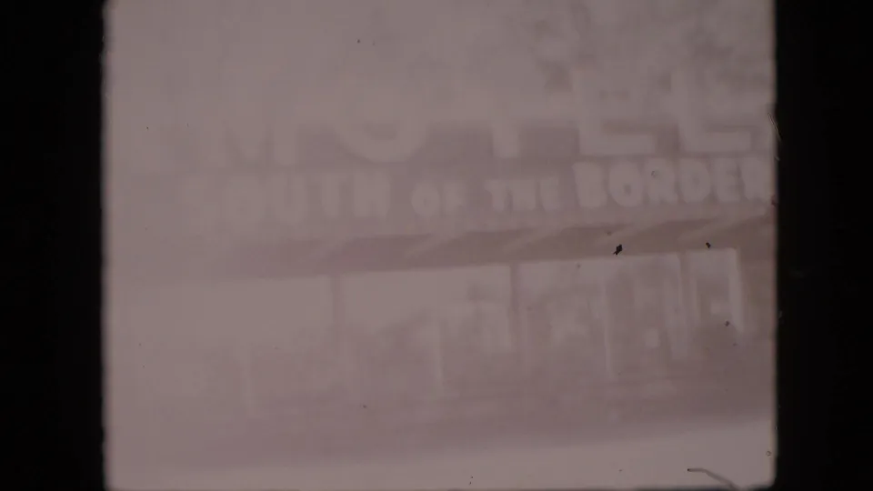 Faded 1958 8mm frame, metadata-located in Pennsylvania, showing the South of the Border Motel sign partly washed out above a covered frontage.
