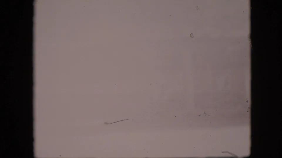Faded 8mm frame from the 1958 Pennsylvania clip with the scene mostly washed out and only faint exterior detail visible near the right side.