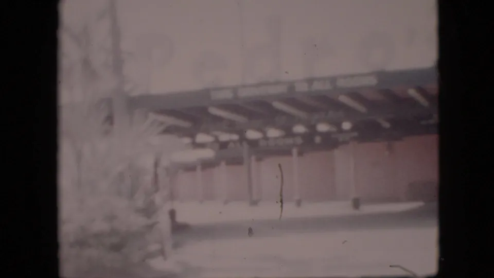 1958 Pennsylvania 8mm frame showing a low building with canopy, columns, driveway, landscaping, and partially legible sign lettering along the entrance area.