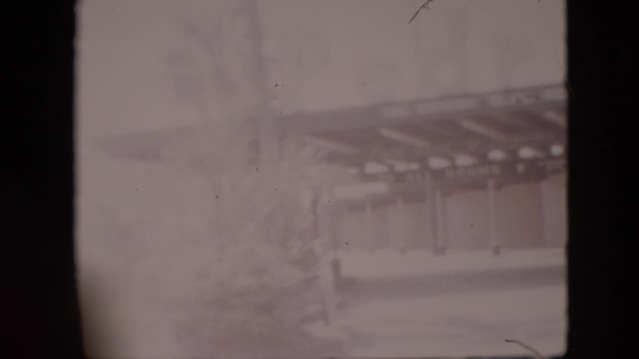 Faded 1958 Pennsylvania 8mm frame showing what appears to be a roadside restaurant or similar establishment with a covered entrance, seen through soft focus and heavy film wear.