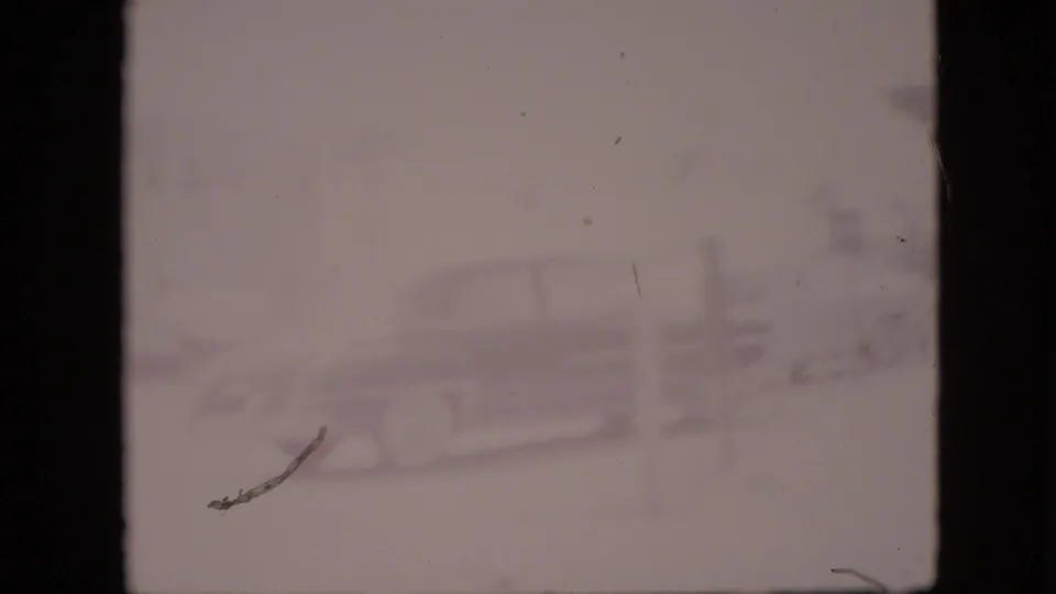 Very faded 1958 Pennsylvania 8mm frame with a faint classic automobile near the roadside establishment, partially obscured by exposure washout and film damage.