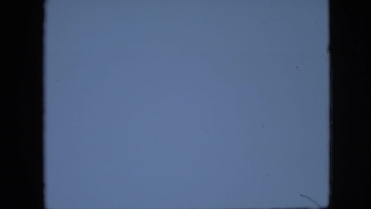 A pale blue abstract 8mm frame from the supplied 1958 Pennsylvania clip, with dark film-edge borders, soft grain, and small specks.