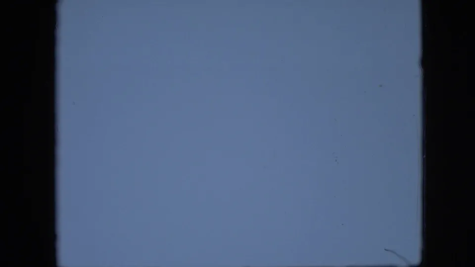 A pale blue abstract 8mm frame from the supplied 1958 Pennsylvania clip, with dark film-edge borders, soft grain, and small specks.