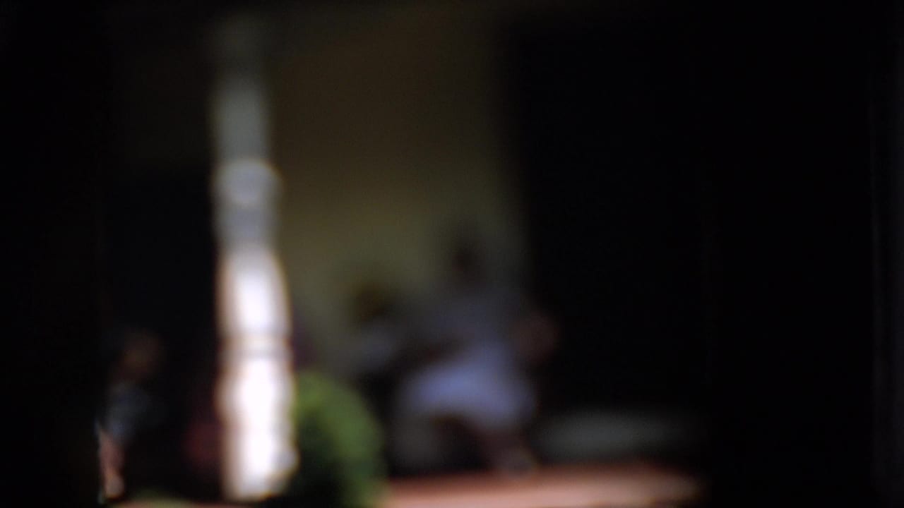 Two women sit on a porch in soft focus with a bright column in the foreground.