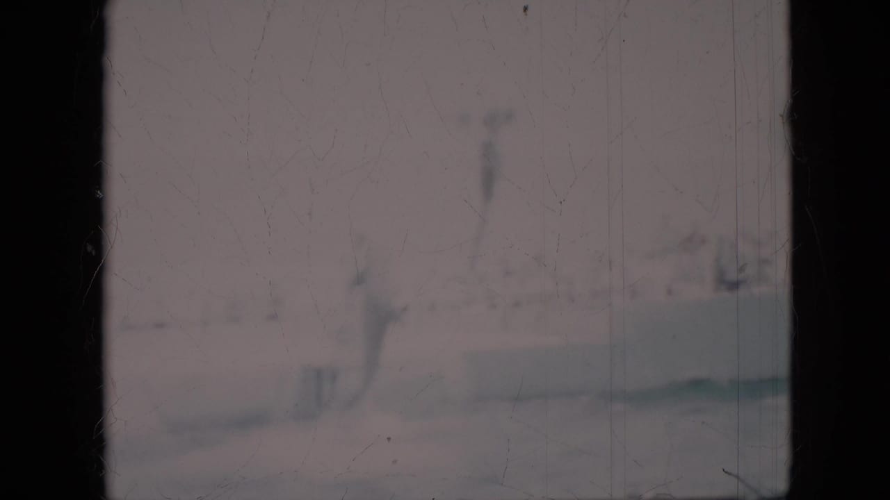 1958 Pennsylvania 8mm frame showing murky green water with faint fish-like forms, pale bottom reflections, and visible film scratches.