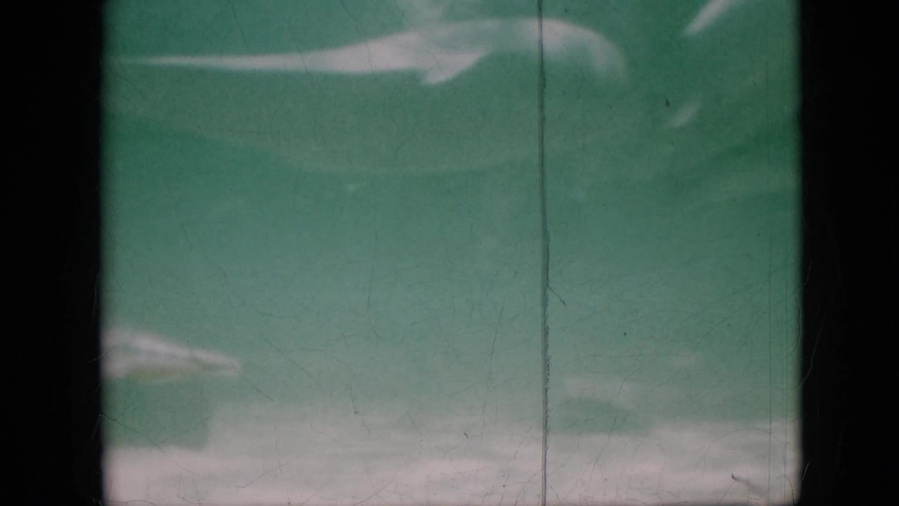 1958 Pennsylvania 8mm frame showing a green-tinted underwater view with a pale bottom edge, soft haze, black film border, and vertical scratch marks.