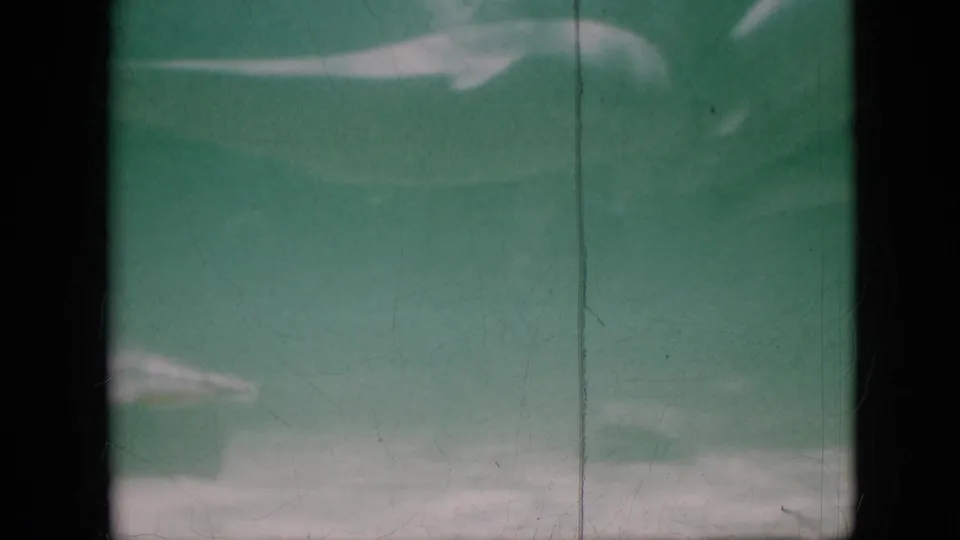 1958 Pennsylvania 8mm frame showing a green-tinted underwater view with a pale bottom edge, soft haze, black film border, and vertical scratch marks.