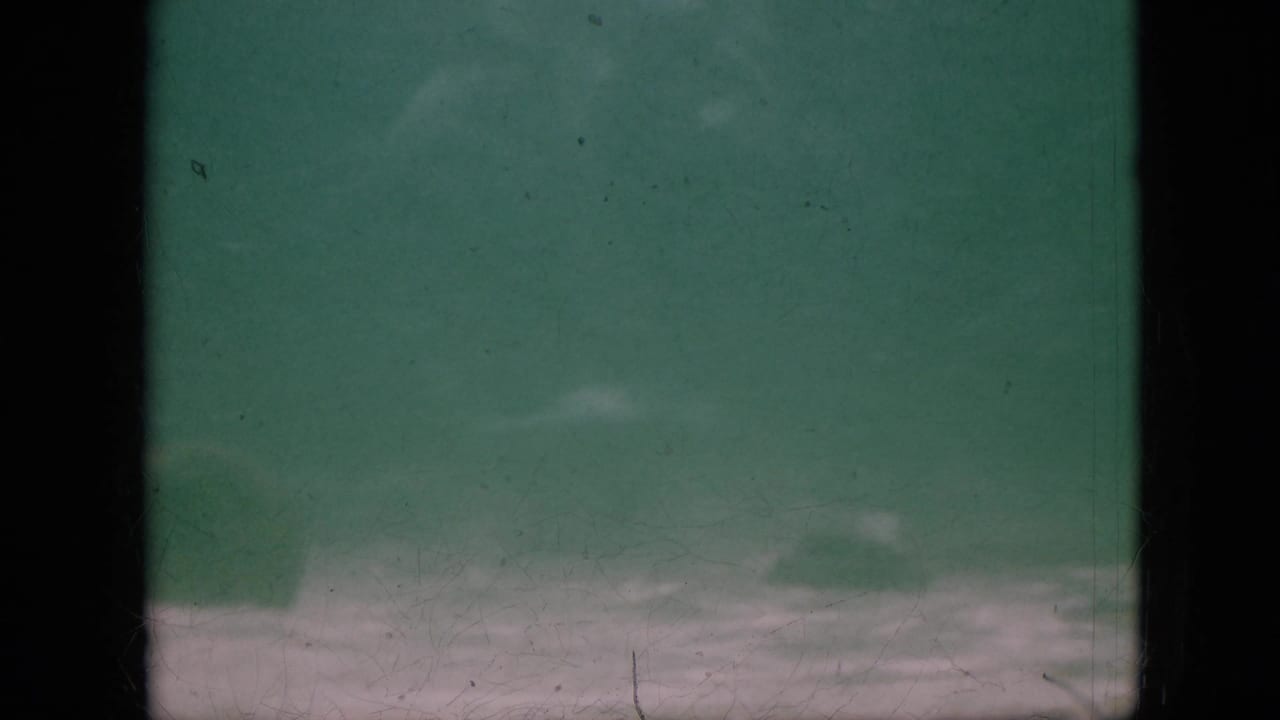1958 Pennsylvania 8mm frame with green underwater haze, a dark vertical band through the center, pale bottom area, and visible film wear.