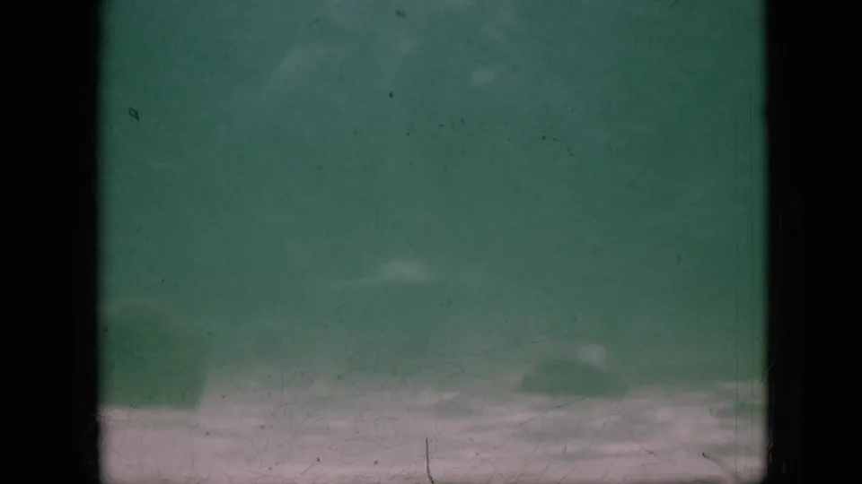 1958 Pennsylvania 8mm frame with green underwater haze, a dark vertical band through the center, pale bottom area, and visible film wear.