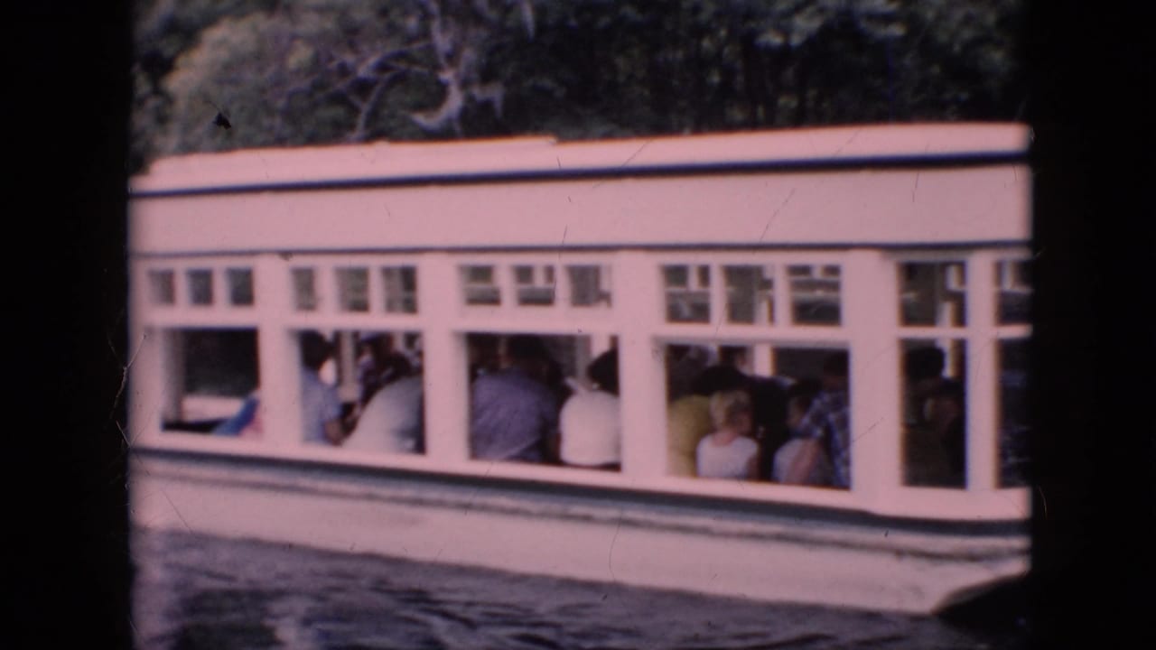 1958 Pennsylvania 8mm frame showing a white windowed tour boat carrying seated passengers along a wooded shoreline.