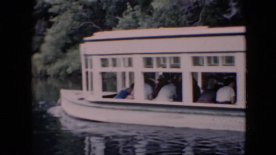 1958 Pennsylvania 8mm frame showing a white passenger boat gliding past trees with seated riders visible through the windows.