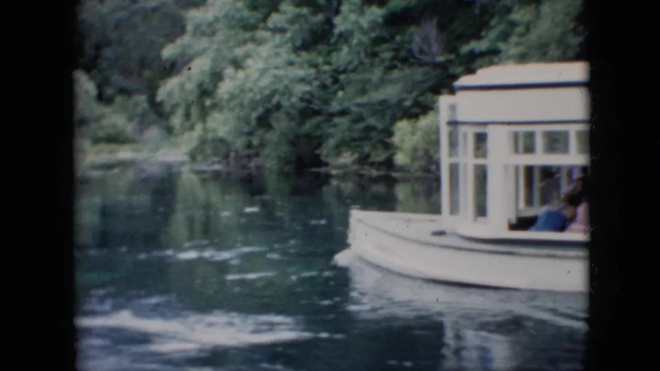 A partial side view of the white tour boat shows passengers near the windows as it moves across calm water in a wooded Pennsylvania river setting.