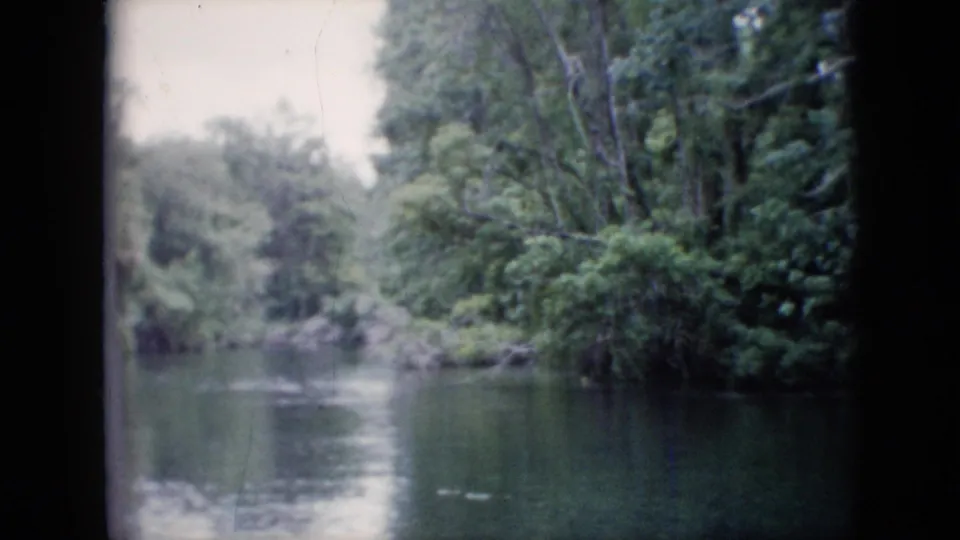 Final 1958 Pennsylvania 8mm frame looking toward calm water and a dense wooded riverbank from a slow moving viewpoint.
