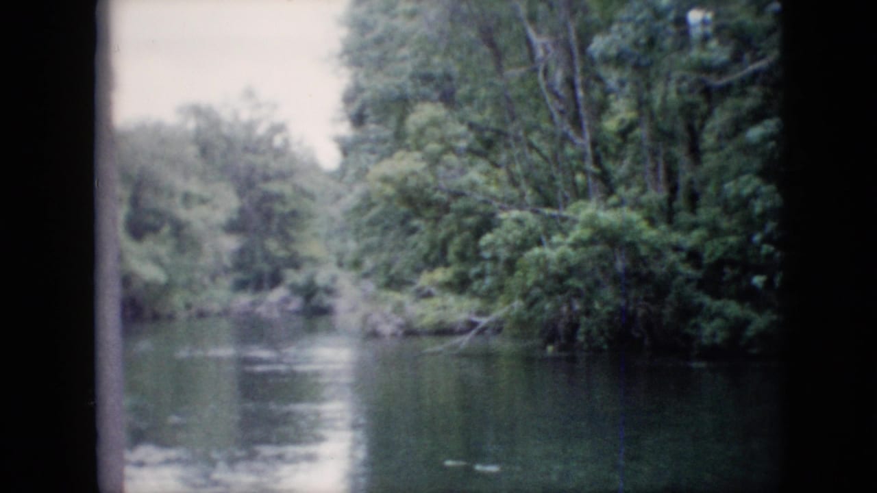 1958 Pennsylvania 8mm home-movie frame showing still river water, wooded banks, muted foliage, and visible scan borders.