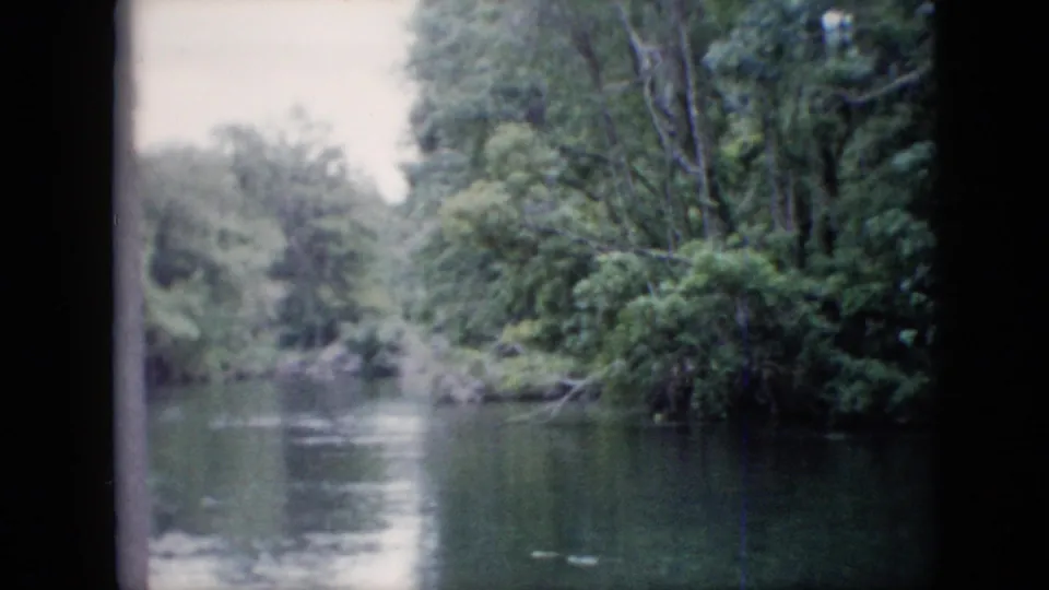 1958 Pennsylvania 8mm home-movie frame showing still river water, wooded banks, muted foliage, and visible scan borders.