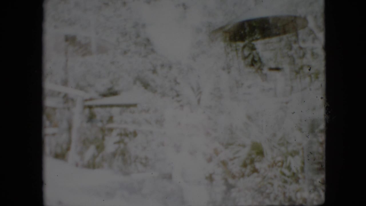 Heavily faded 1958 Pennsylvania 8mm frame showing a snowy outdoor area with indistinct trees, possible structures, and dark gate edges.