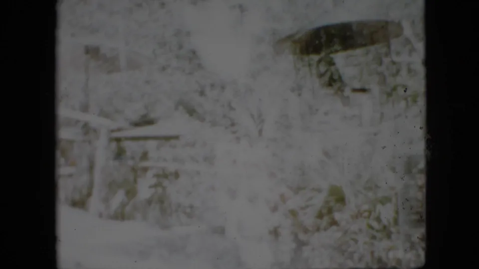 Heavily faded 1958 Pennsylvania 8mm frame showing a snowy outdoor area with indistinct trees, possible structures, and dark gate edges.