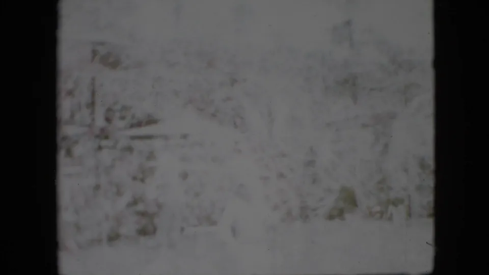 Faded 1958 Pennsylvania winter frame with snow-covered trees and barely visible structures or landscape forms in the background.