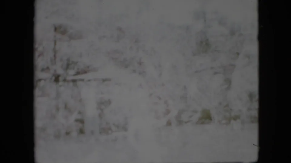 Aged 8mm Pennsylvania winter frame with a pale snowy foreground, vague tree forms, and dark film edges from the scan.