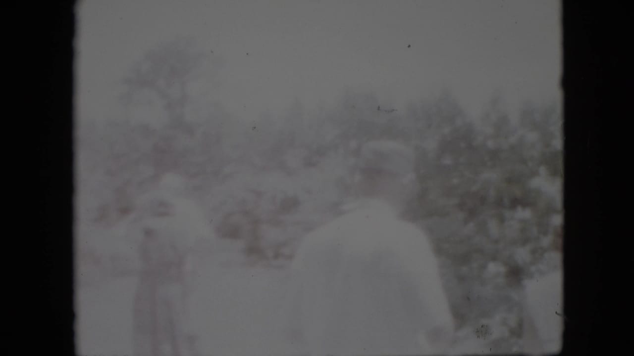 1958 Pennsylvania 8mm frame showing blurred figures overlaid with a snow-covered outdoor landscape, bare trees, bushes, and dark film borders.