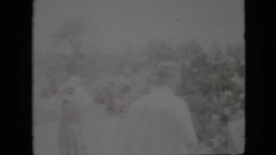 1958 Pennsylvania 8mm frame showing blurred figures overlaid with a snow-covered outdoor landscape, bare trees, bushes, and dark film borders.