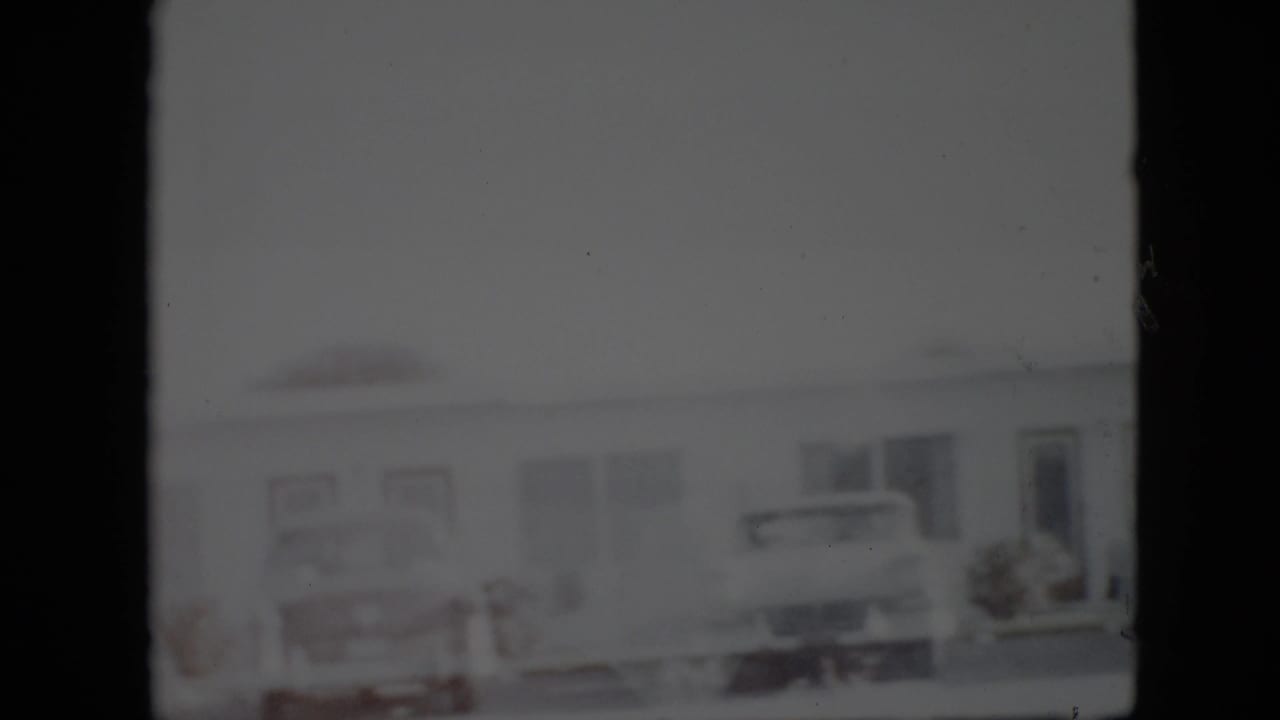 Row of parked cars and a low building facade in soft focus.