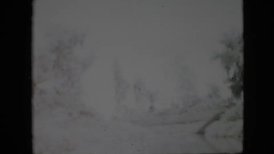 1958 Pennsylvania home-movie frame with bright snow, indistinct winter trees, soft exposure bloom, and dark 8mm border areas.