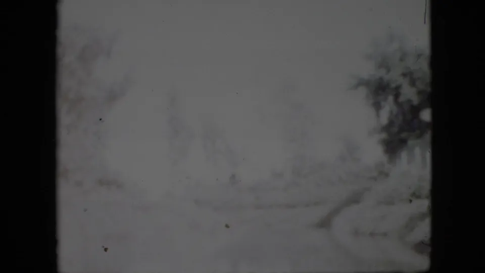 Soft 1958 Pennsylvania winter frame with a pale snow-covered path, leafless trees, and visible 8mm film gate edges.