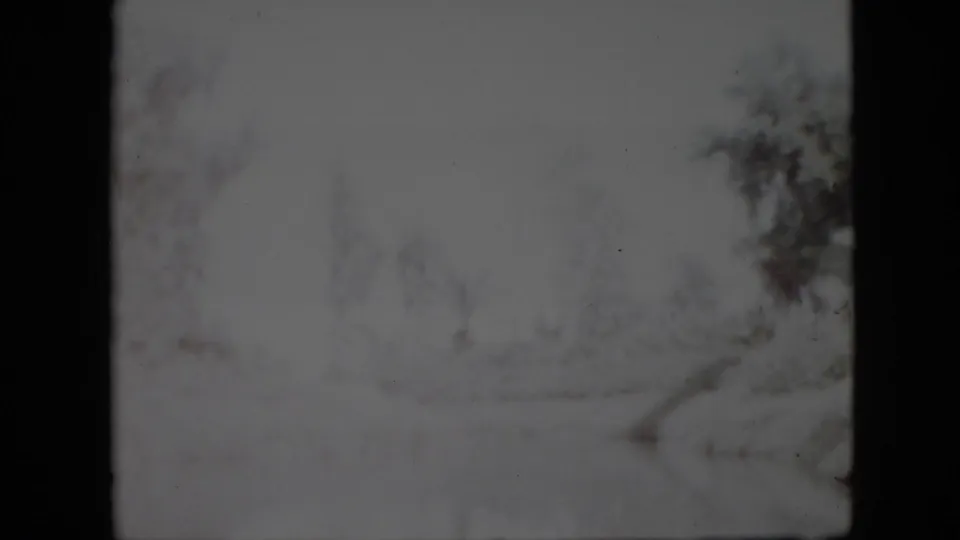 Grainy 8mm frame from Pennsylvania in 1958 showing a subdued snow-covered landscape with bare trees and a path receding through the scene.