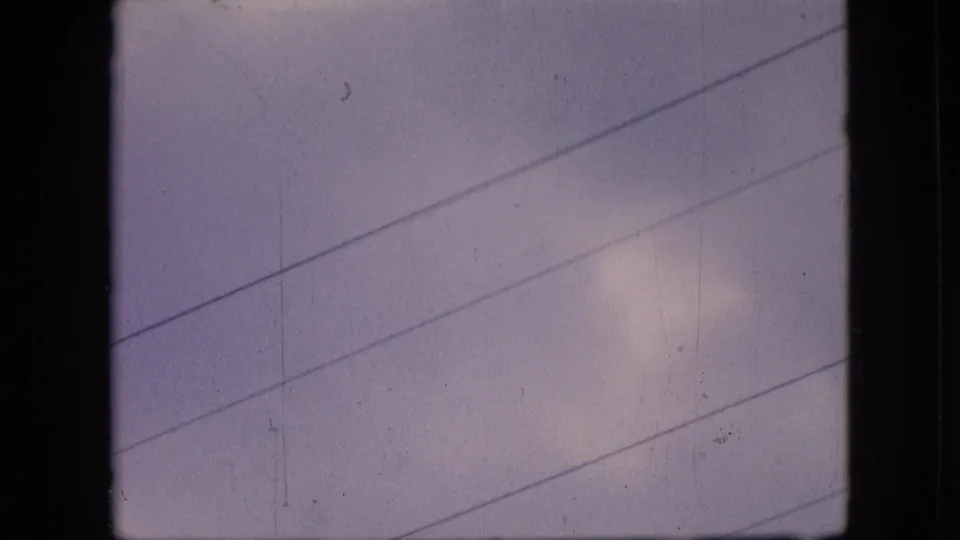 The final 1964 Philadelphia frame holds on the overcast sky and diagonal utility wires after the aircraft has moved out of view, with grain and scratches visible in the scan.