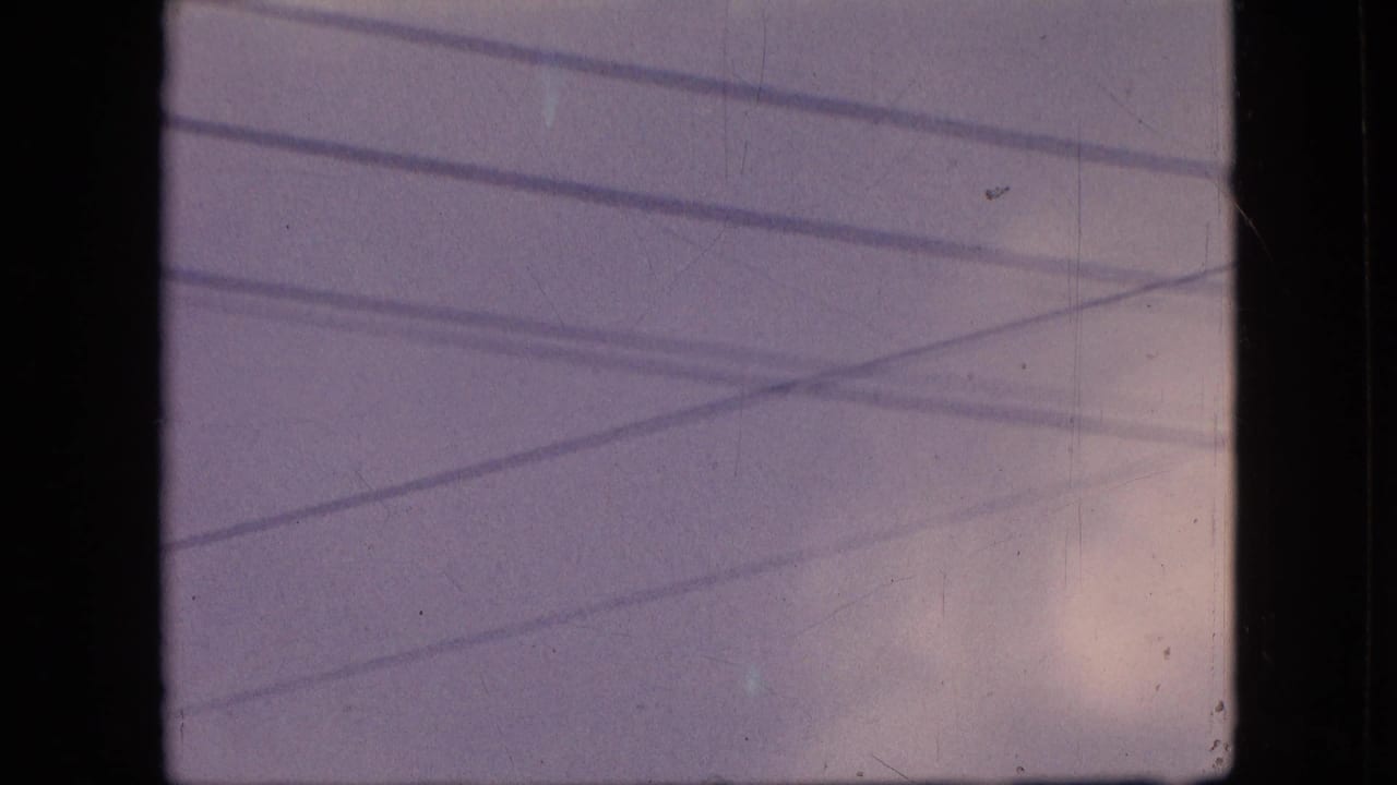 1964 Philadelphia 8mm frame with soft clouds and multiple overhead wires running diagonally and horizontally across the sky.