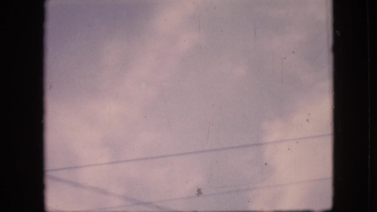 Soft cloud cover with electric wires and visible 8mm film wear.