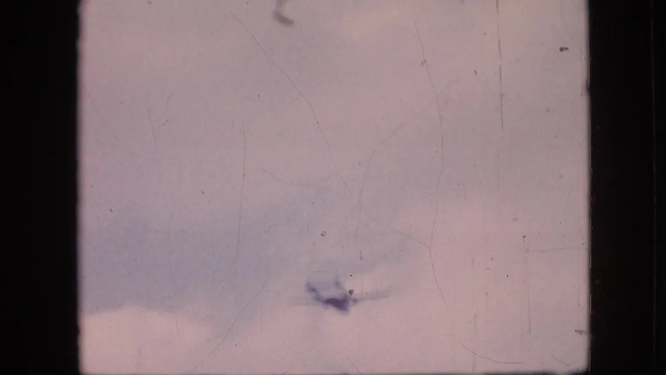 Aircraft appears near the lower edge of a bright, clouded sky in faded 8mm footage from the supplied 1964 Philadelphia clip.